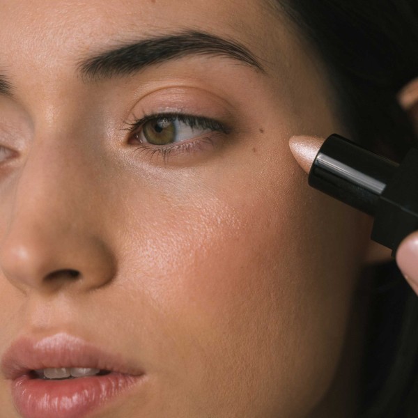 Profile of woman applying highlighter of intense rose color
