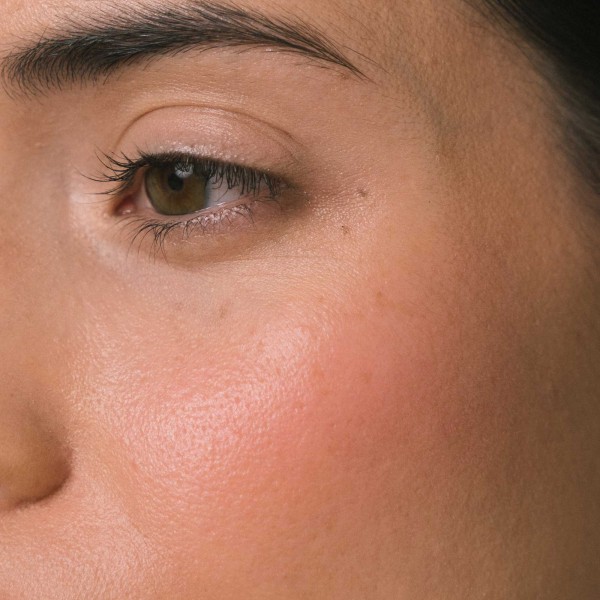 Woman cheek close-up wearing powder blush color intense rose