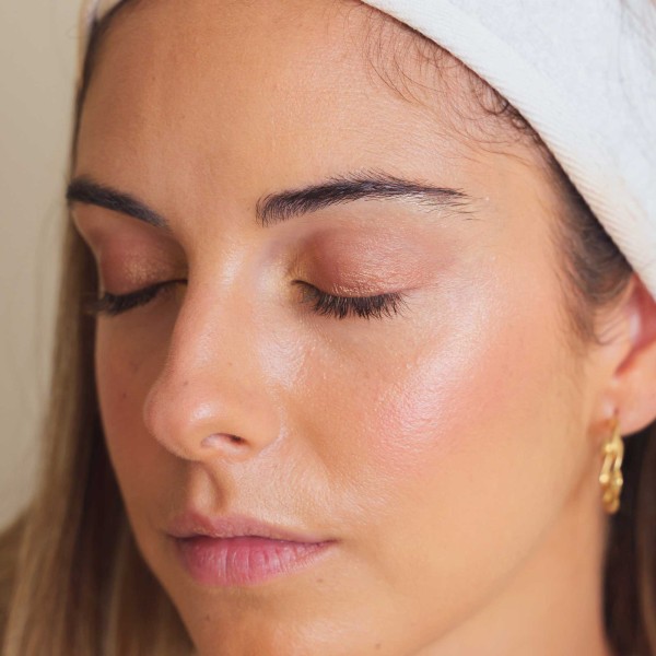 Perfil de mujer maquillada con el iluminador toque dorado orgánico y bio